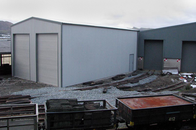 A dual-doored grey building on a train yard